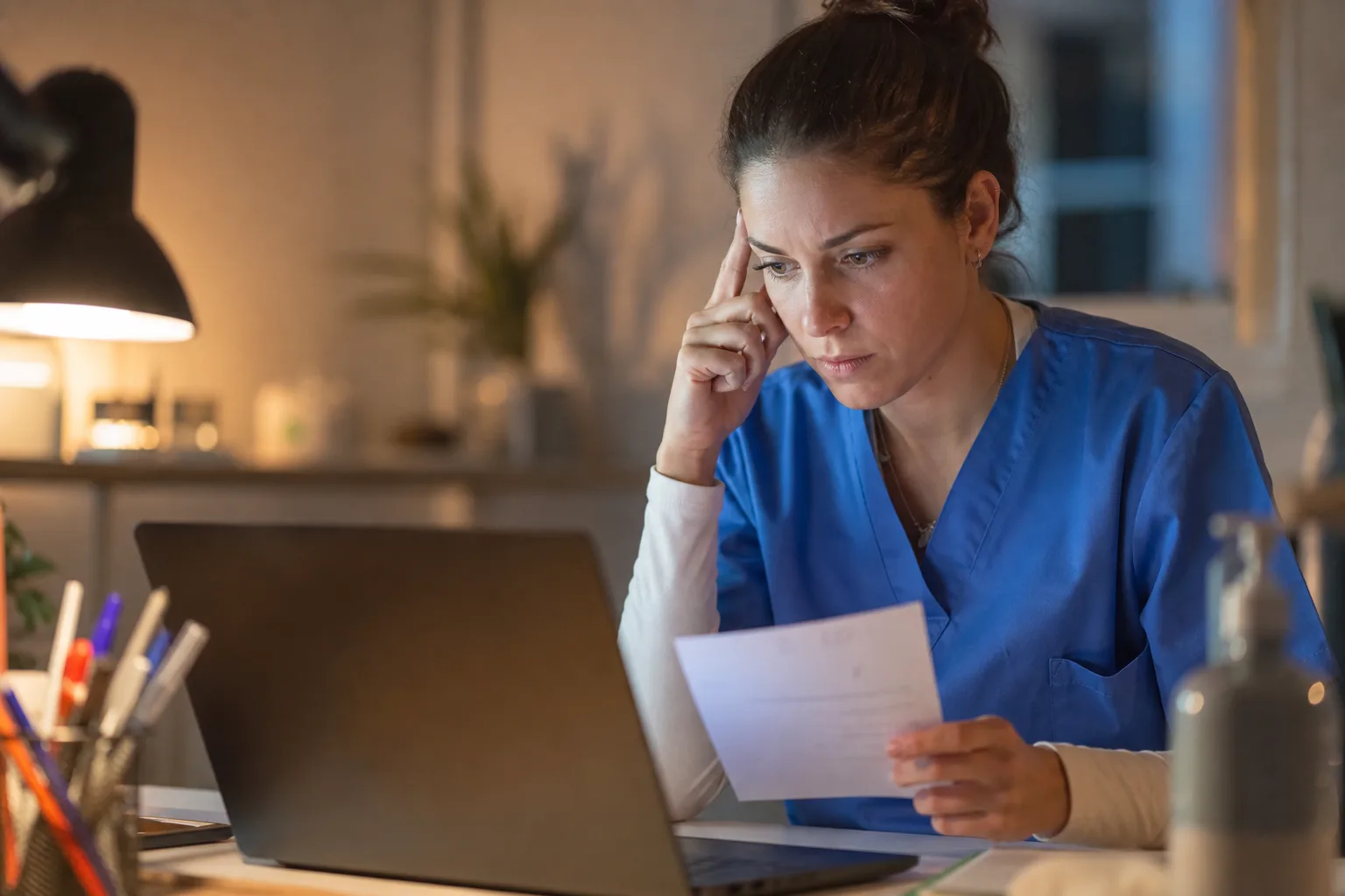Jeune IDEL le soir devant un ordinateur, concentrée sur un cas de cotation difficile